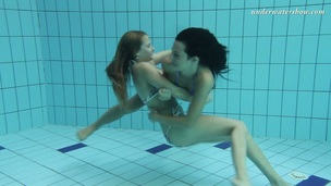 2 tempting mermaids caressing every other underwater